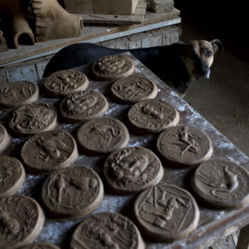 In this Friday, Oct. 13, 2017 photo a dog stands next to ceramic medallions based on ancient Greek coins in Haralambos Goumas' sculpture and ceramic workshop, in the Egaleo suburb of Athens. (AP Photo/Petros Giannakouris)