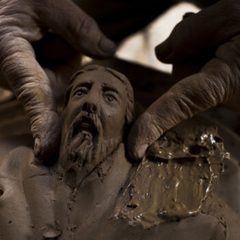 In this Friday Dec. 15, 2017 photo, sculptor and ceramIcist Haralambos Goumas works on a terracotta flower pot decorated with the face ancient Greek god of the sea, Poseidon, at his workshop in the Egaleo suburb of Athens. (AP Photo/Petros Giannakouris)