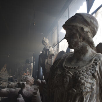 In this Friday, Nov. 20, 2017 photo, smoke the terracotta statue of Athens, ancient Greek goddess of wisdom and patron of Athens, left, stands in front of Apollo, god of light and music, in Haralambos Goumas' sculpture and ceramic workshop, in the Egaleo suburb of Athens. (AP Photo/Petros Giannakouris)