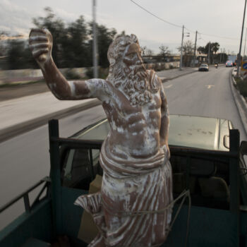 In this Tuesday, Dec 19, 2017 photo, a pickup track drives on a street of Athens carrying a terracotta statue of Zeus, chief among the ancient Greek gods, made by sculptor and ceramicist Haralambos Goumas. (AP Photo/Petros Giannakouris)