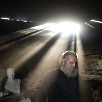 In this Friday, Nov. 20, 2017 photo, rays of sunlight shine on sculptor and ceramicist Haralambos Goumas as he works in his workshop, in the Egaleo suburb of Athens. (AP Photo/Petros Giannakouris)