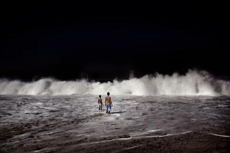 Francesco Zizola - Two boys await the crushing of a big wave against the shore of the Arpoador beach.