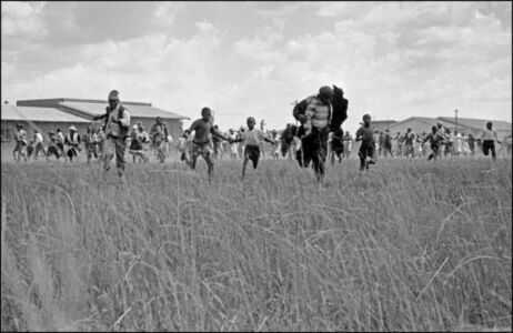 Ian Berry - South Africa. Transvaal. Sharpeville. Unarmed blacks run away from the police who are shooting and killing a peaceful gathering. Here a young boy shields himself from the bullets by pulling up his jacket over his head. 1960.